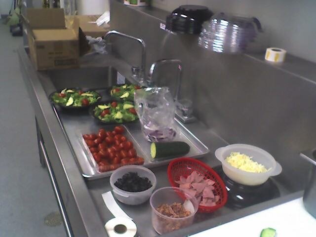 Mise en place de ensaladas en mesada de acero